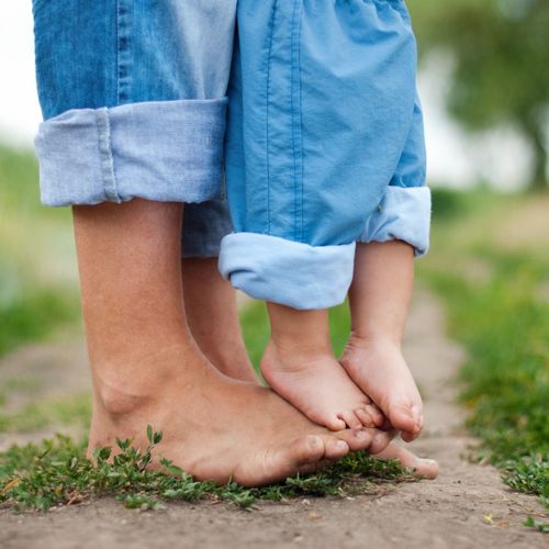 A young child balancing on their parents feet