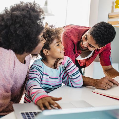 Two parents happily chatting with their child over a book